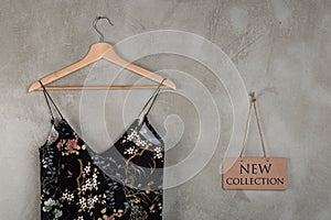 Fashion and shopping concept - blackboard with text New Collection and little black dress in floral pattern on a hanger