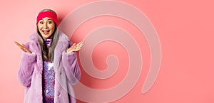 Fashion and shopping concept. Cheerful asian elderly woman in purple stylish coat looking surprised, hear good news and