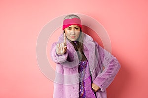 Fashion and shopping concept. Serious asian senior woman showing not so fast gesture, shaking extended finger to stop or