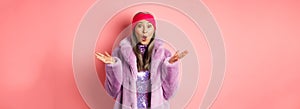 Fashion and shopping concept. Surprised elderly asian woman in stylish fake-fur coat and headband looking amazed at