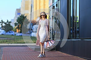 Fashion Shopping Girl Portrait. Beautiful girl in sunglasses. After day shopping. Girl with shopping bags. Shopper. Sales