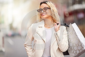 Fashion, shopping and woman in city with bag, sunglasses and retail therapy with financial freedom. Smile, walking and