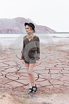 Fashion shot of a beautiful girl in a black hat is removed in the desert for the magazine photo