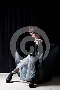 Fashion shot of a beautiful young girl with a cheeky short hair style hipster in black velvet jacket in a studio on a black backgr