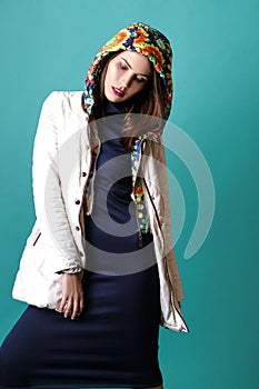 Fashion shot of a woman in white coat, blue drees in studio on green background