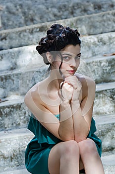 Fashion slim woman wearing green strapless short dress sitting on old and dirty cement stairs