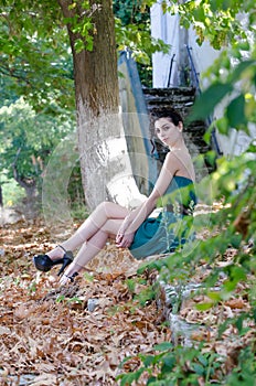 Fashion slim woman wearing green strapless short dress sitting sidewalk,