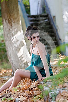 Fashion slim woman wearing green strapless short dress sitting sidewalk