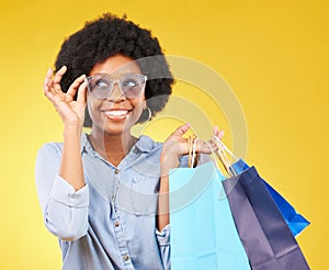 Fashion, smile and black woman with shopping bags, happy and excited for sale in studio on yellow background. Sunglasses