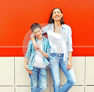 Fashion smiling mother with son teenager together on red