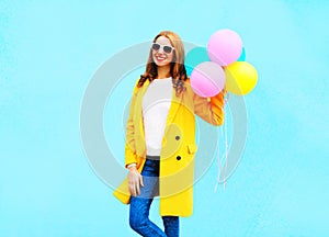 Fashion smiling woman holds an air balloons in yellow coat