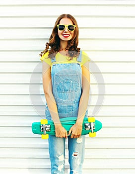 Fashion smiling woman with a skateboard posing over white background