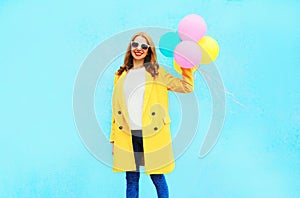 Fashion smiling young woman holds an air balloons in yellow coat