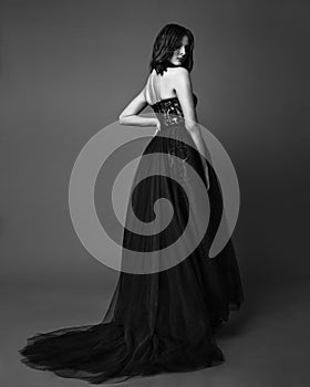 Fashion studio photo of elgant woman in long black dress. Black