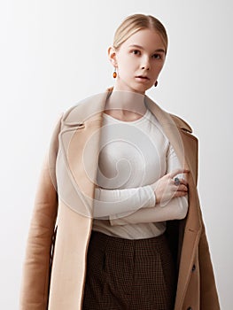 Fashion studio photo of young beautiful lady in beige coat on white background. Total beige. Fashion look book