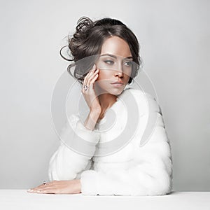 Beautiful woman with elegant hairstyle in white fur coat