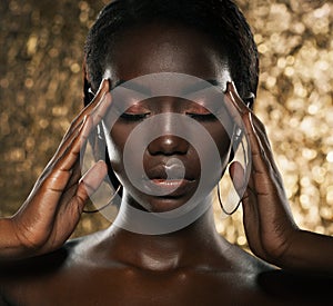 Fashion studio portrait of an extraordinary beautiful african american model with closed eyes over golden background