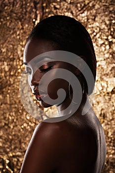 Fashion studio portrait of an extraordinary beautiful african american model with closed eyes over golden background