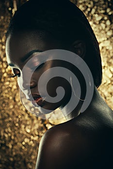 Fashion studio portrait of an extraordinary beautiful african american model with closed eyes over golden background