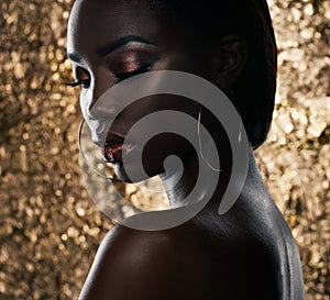 Fashion studio portrait of an extraordinary beautiful african american model with closed eyes over golden background