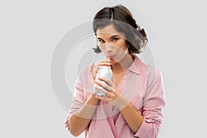 Woman drinking soda from can with paper straw