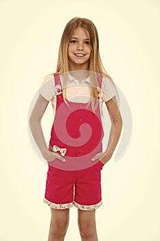 Fashion style and trend. Small girl smile in pink jumpsuit isolated on white. Child smiling with long blond hair. Kid