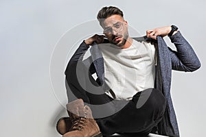 Fashion stylish man with glasses pulling and fixing casual hoodie