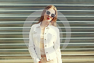 Fashion stylish woman in sunglasses and white denim jacket