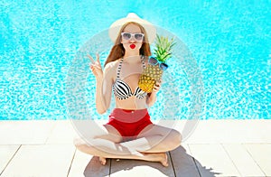 Fashion, summer holidays concept - woman with pineapple having fun on a blue water pool