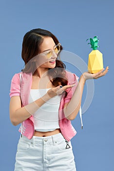 Fashion summer portrait Asian girl in sunglasses and paper pineapple over blue background