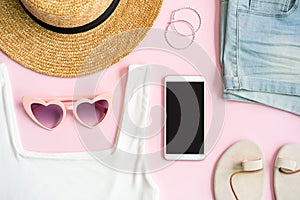 Fashion summer women`s clothes set with accessories on pink background with empty screen smart phone, Flat lay, Top view