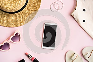 Fashion summer women`s clothes set with accessories on pink background with empty screen smart phone, Flat lay, Top view