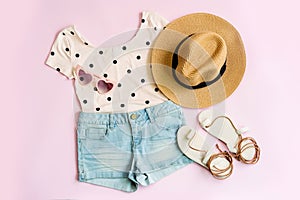 Fashion summer women`s clothes set with accessories on pink background, Flat lay, Top view