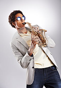 Fashion, sunglasses and man with saxophone in studio with classy, trendy and stylish outfit. Style, handsome and male