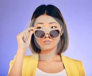 Fashion, sunglasses and a model asian woman on a purple background in studio for trendy style. Face, shades and attitude