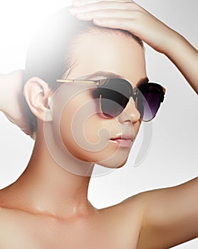 Fashion sunglasses. Sexy woman in swimsuit with golden sunglasses and natural makeup. Glamour shot of a beautiful model