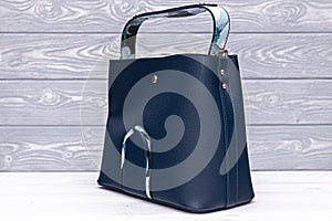 Fashion synthetic leather blue handbag on a wooden background. Eco leather.
