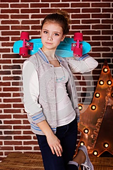 Fashion teenager girl is holding blue skateboard