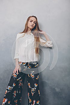 Fashion teenager girl standing against blue textured grunge wall background.