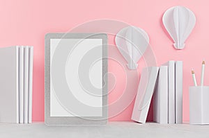 Fashion trendy office desk - white stationery, blank tablet touch computer and decorative origami aerostats on soft light pink.