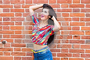 Fashion and urban style concept - Portrait of a beautiful woman in blue jeans against a white brick wall with copy space