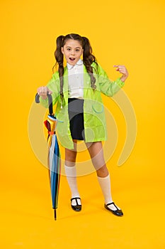 She a fashion victim. Cute schoolchild pointing finger with fashion look on yellow background. Little child in raincoat