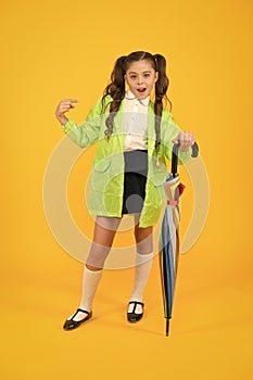 She a fashion victim. Cute schoolchild pointing finger with fashion look on yellow background. Little child in raincoat