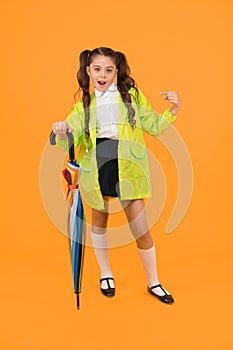 She a fashion victim. Cute schoolchild pointing finger with fashion look on yellow background. Little child in raincoat