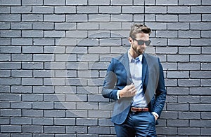 Fashion, wall and man with sunglasses for confidence, trendy style and professional clothes. Male person, eyewear and