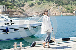 Fashion whilte outfit of trendy beautiful laughing woman in sunglasses posing on the white yacht background
