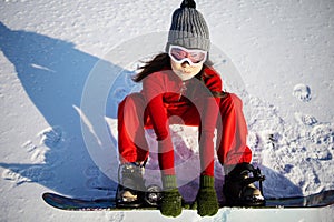 Fashion winter photo of beautiful asian woman in sport clothes posing with snowboard in forest