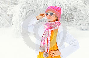 Fashion winter portrait young woman wearing a colorful knitted hat scarf over snowy