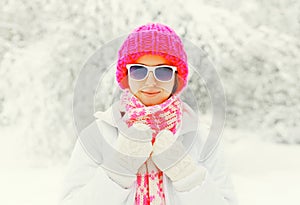 Fashion winter portrait young woman wearing colorful knitted hat, sunglasses over snowy background