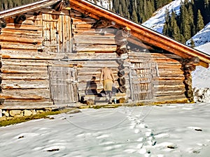 Fashion winter woman ejpying the wooden house in the snow of the alps